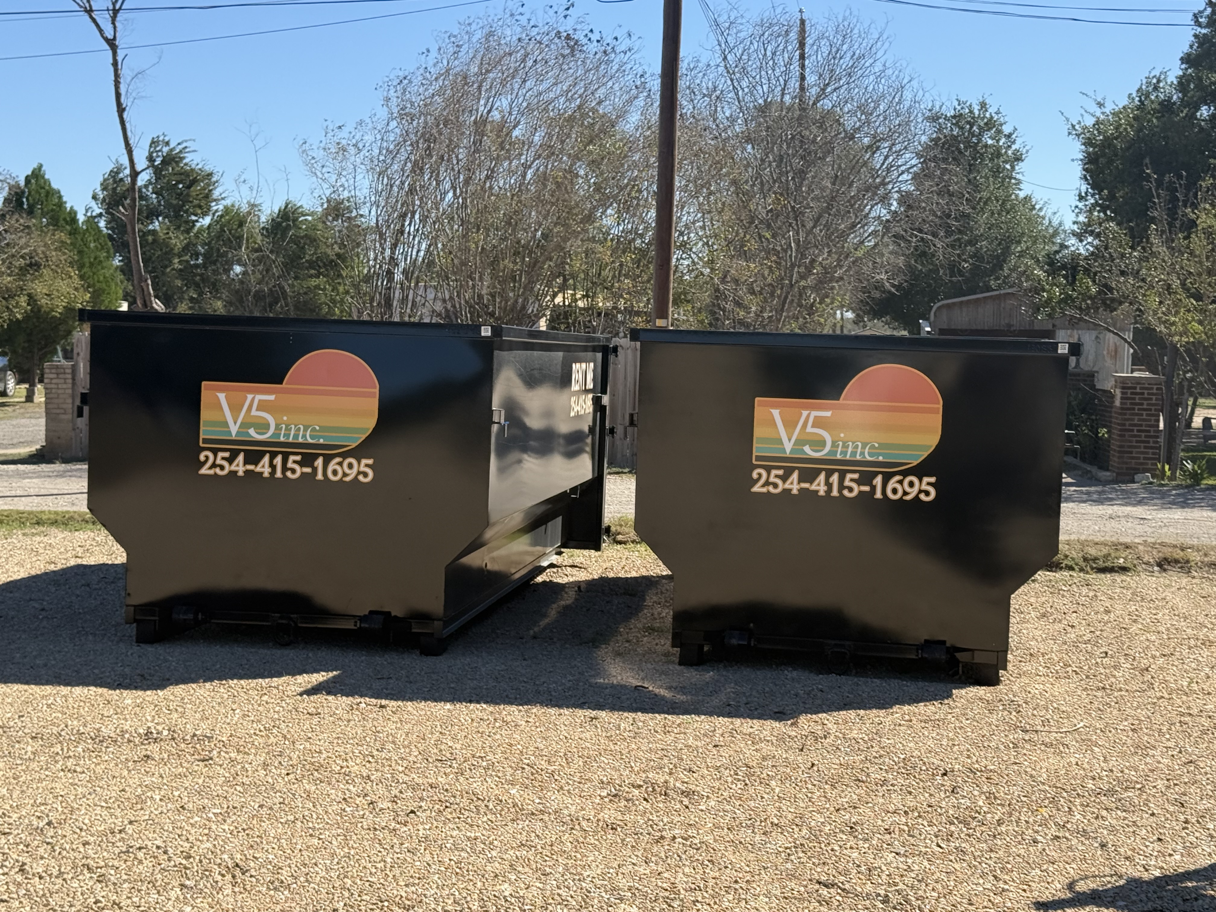 Two V5 Inc. branded dumpsters side by side